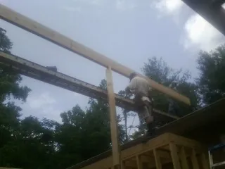 Carpenter setting a ridge beam over a new addition frame — Ice Dam Removal by Roofing Brothers in Rowlett