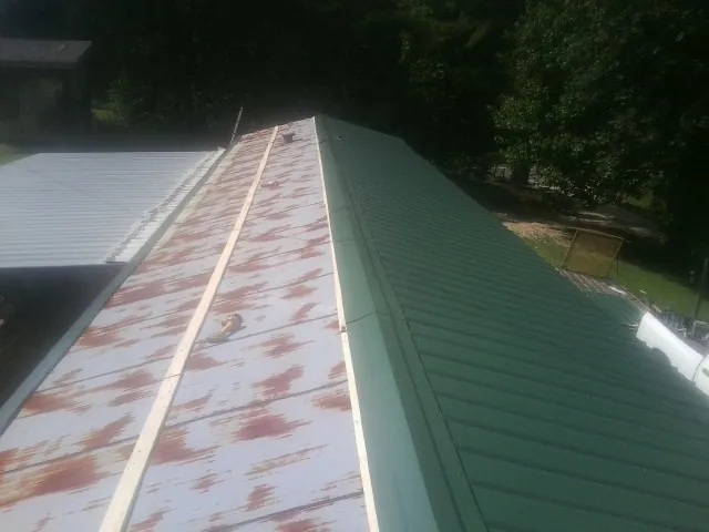 Old rusted panels beside newly installed green metal roofing — Wind Damage Roof Repair by Roofing Brothers in Rowlett
