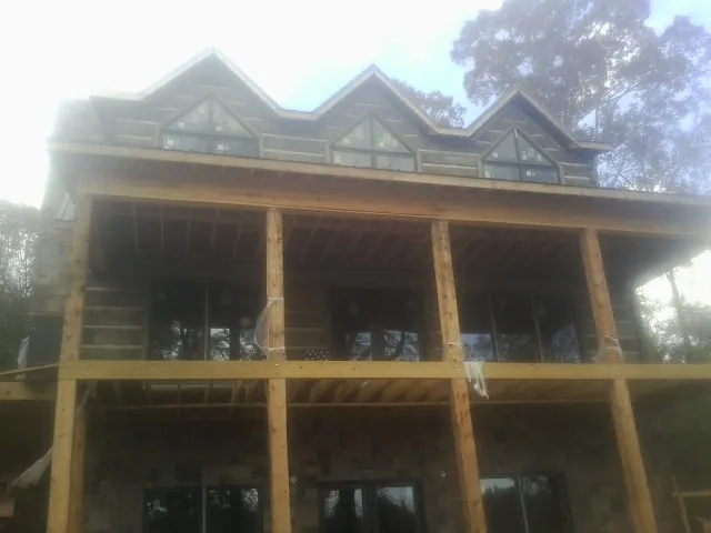 Dormers and porch framing on a large log home under construction — Roof Coating work by our crew in Rowlett