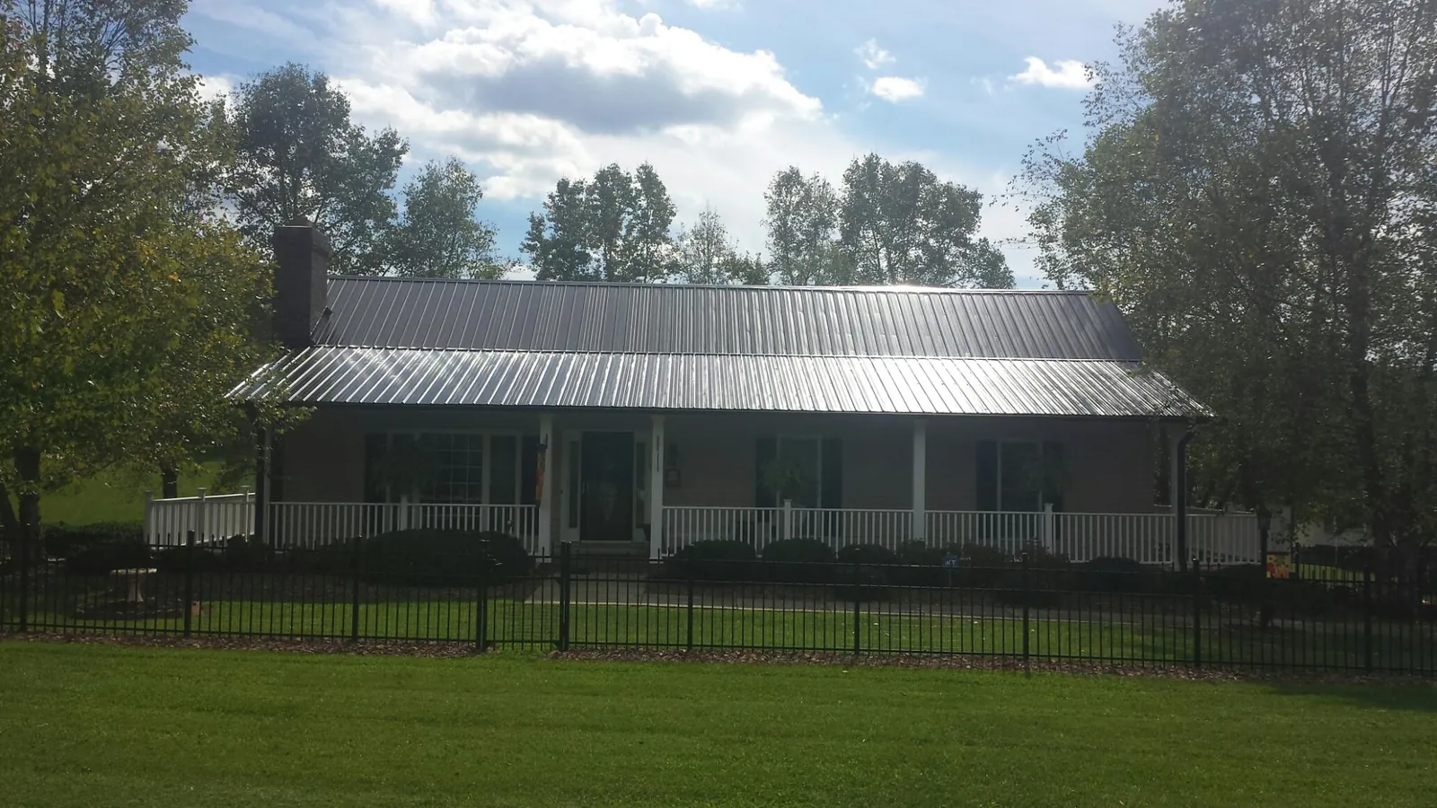 Gray metal roof on a brick ranch with a full width front porch — Gutter Guard Installation work by our crew in Rowlett